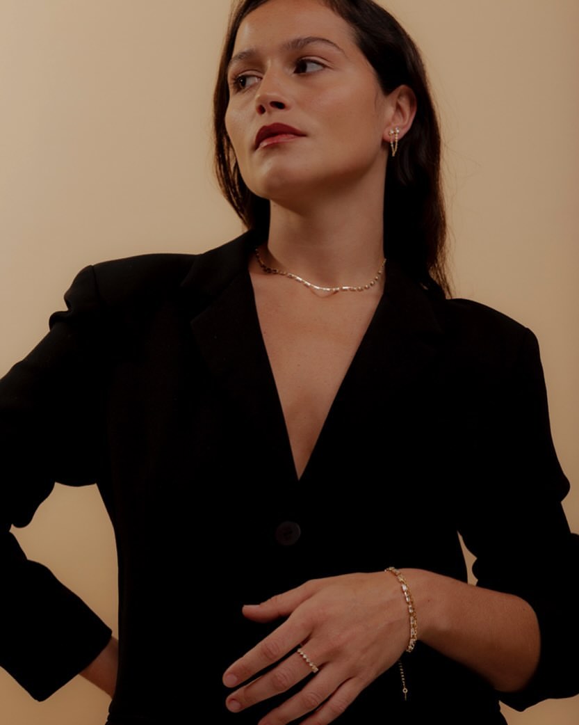 Pulseiras: pulseira e anéis dourados usados por uma mulher de blazer preto